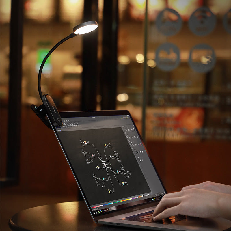 Laptop with a clip-on light on a blurred cafe background